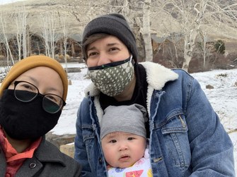 Shinah Lee and Natalie Gualy, LGBTQIA+ Affinity Program participants, holding their baby Carmen outside in the snow.